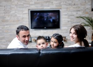 family wathching flat tv at modern home indoor